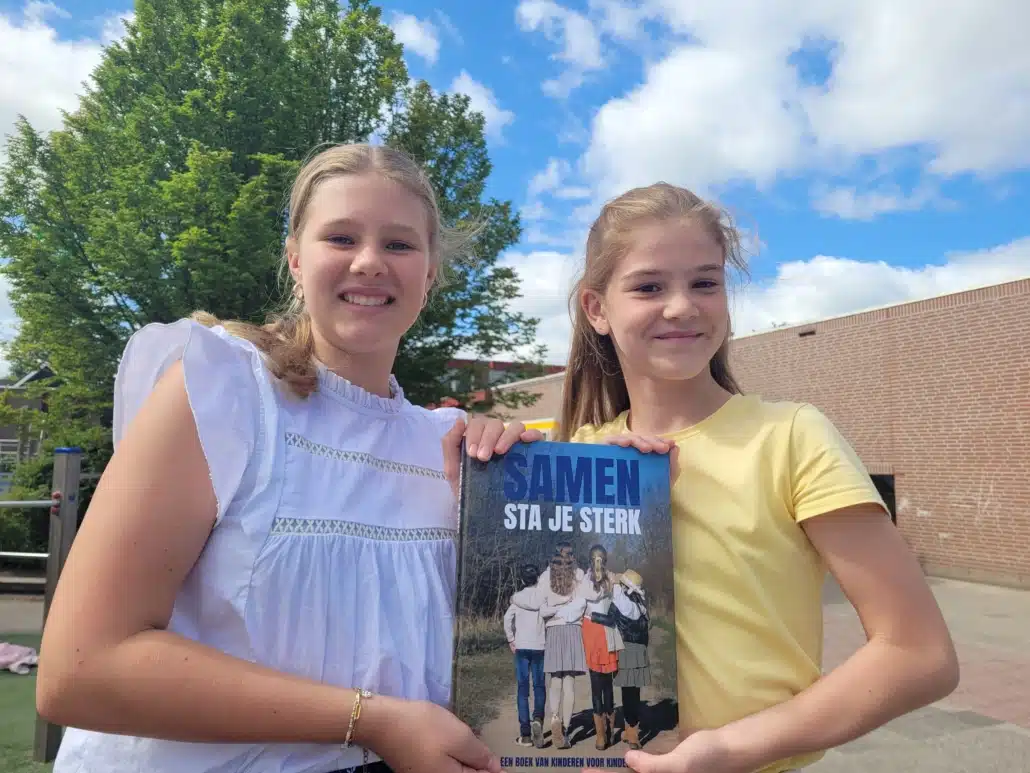 Evi en Lisa poseren met het boek 'Samen sta je sterk'