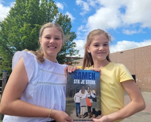 Evi en Lisa poseren met het boek 'Samen sta je sterk'