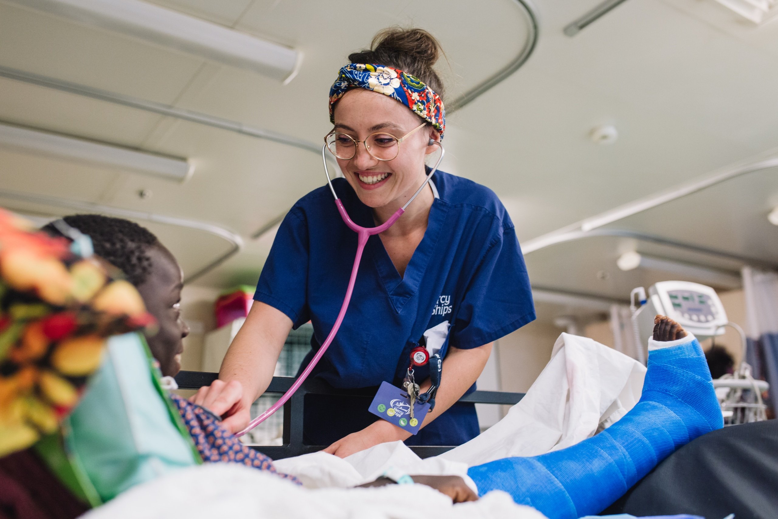 verpleegkundige bij het bed van een jonge patiënt met een been in het gips