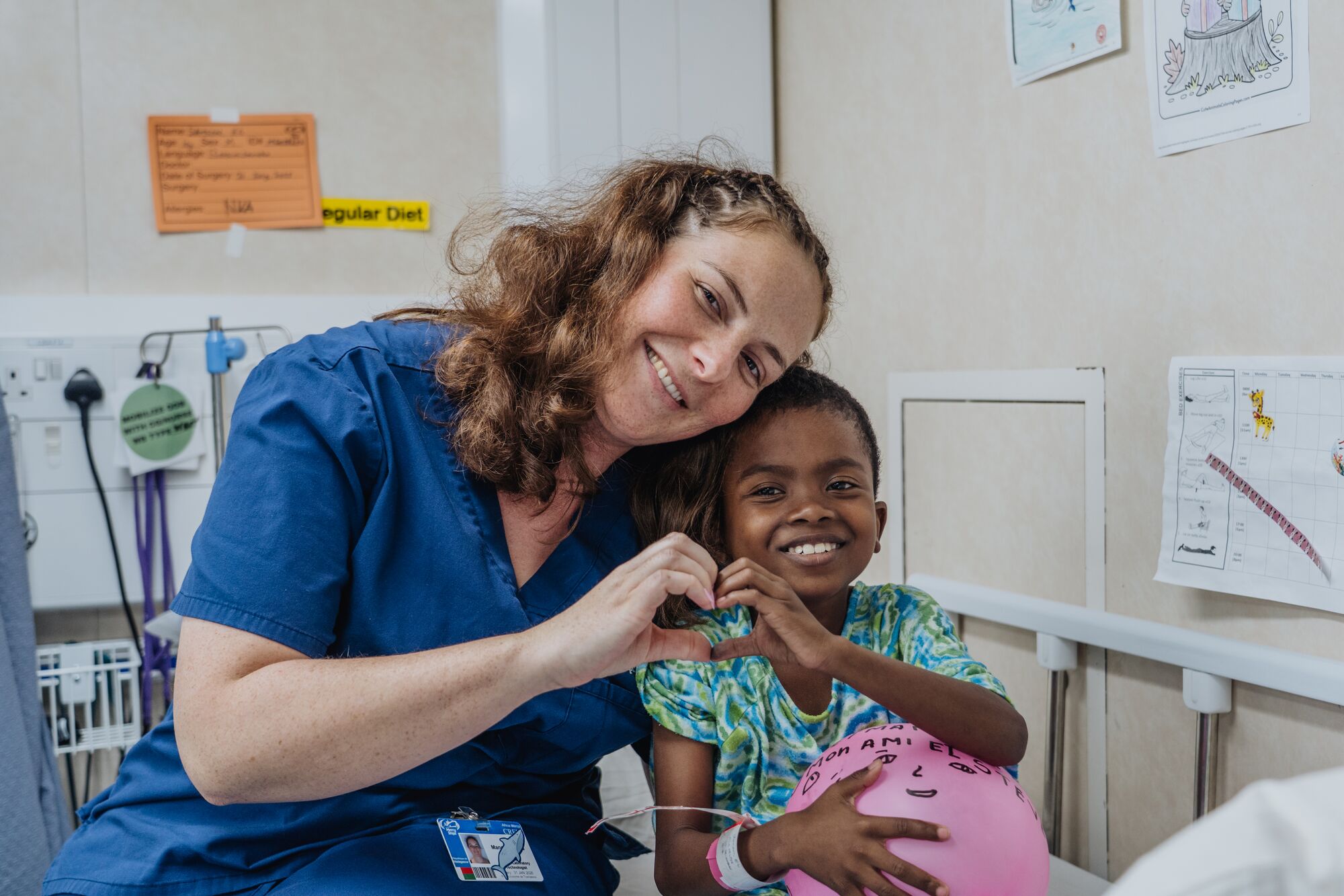 Vrijwilliger maakt hartje met haar hand en die van een patiënt