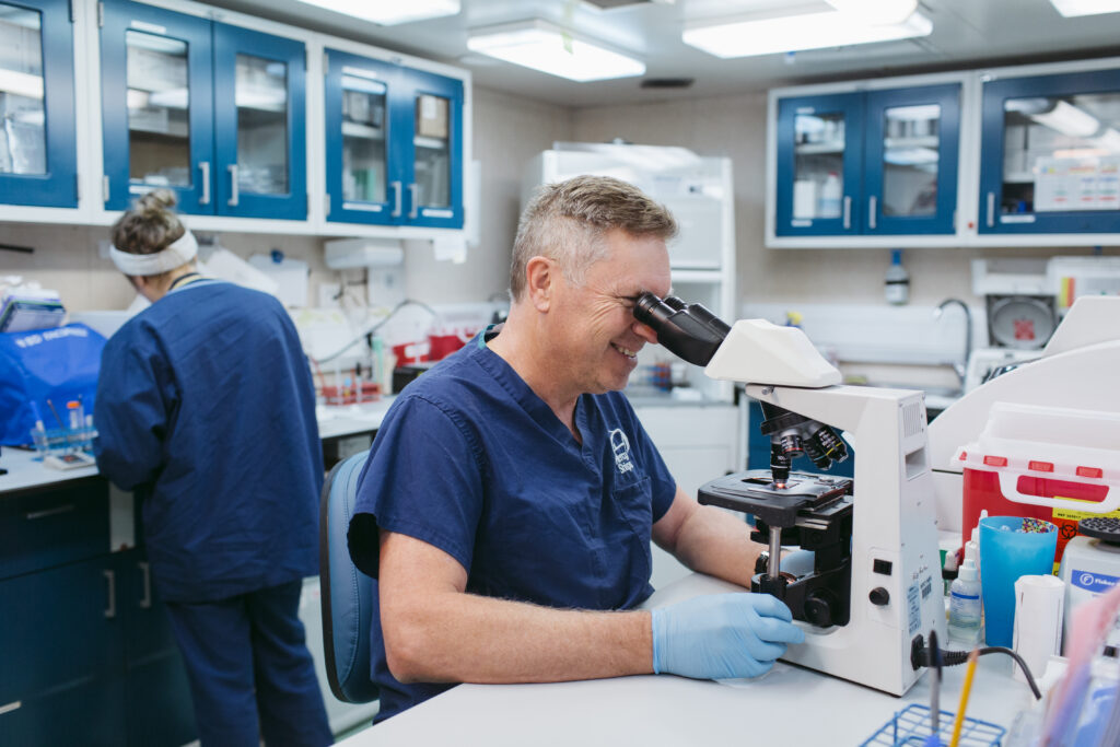foto van een medisch vrijwilliger achter een microscoop