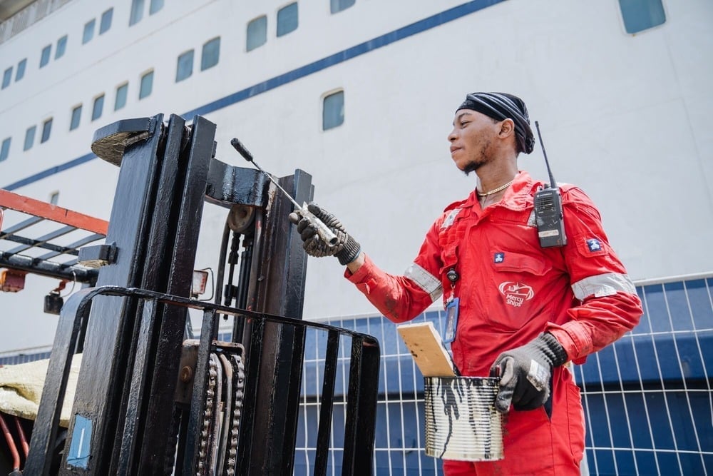 Een vrijwilliger is bezig met onderhoud aan een heftruck